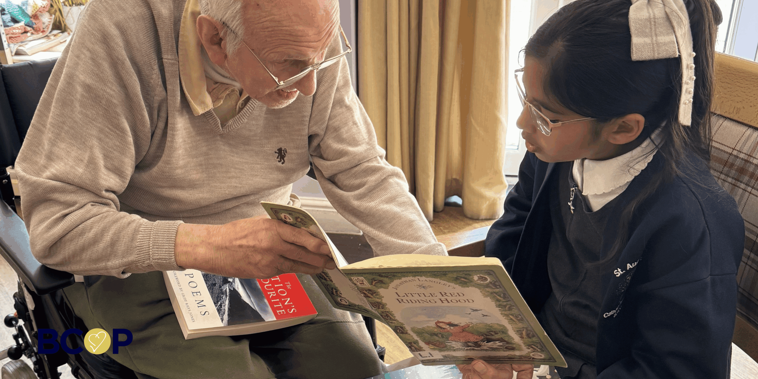 Pupil form St Augustine's pPrimary school reading to a Robert Harvey House resident