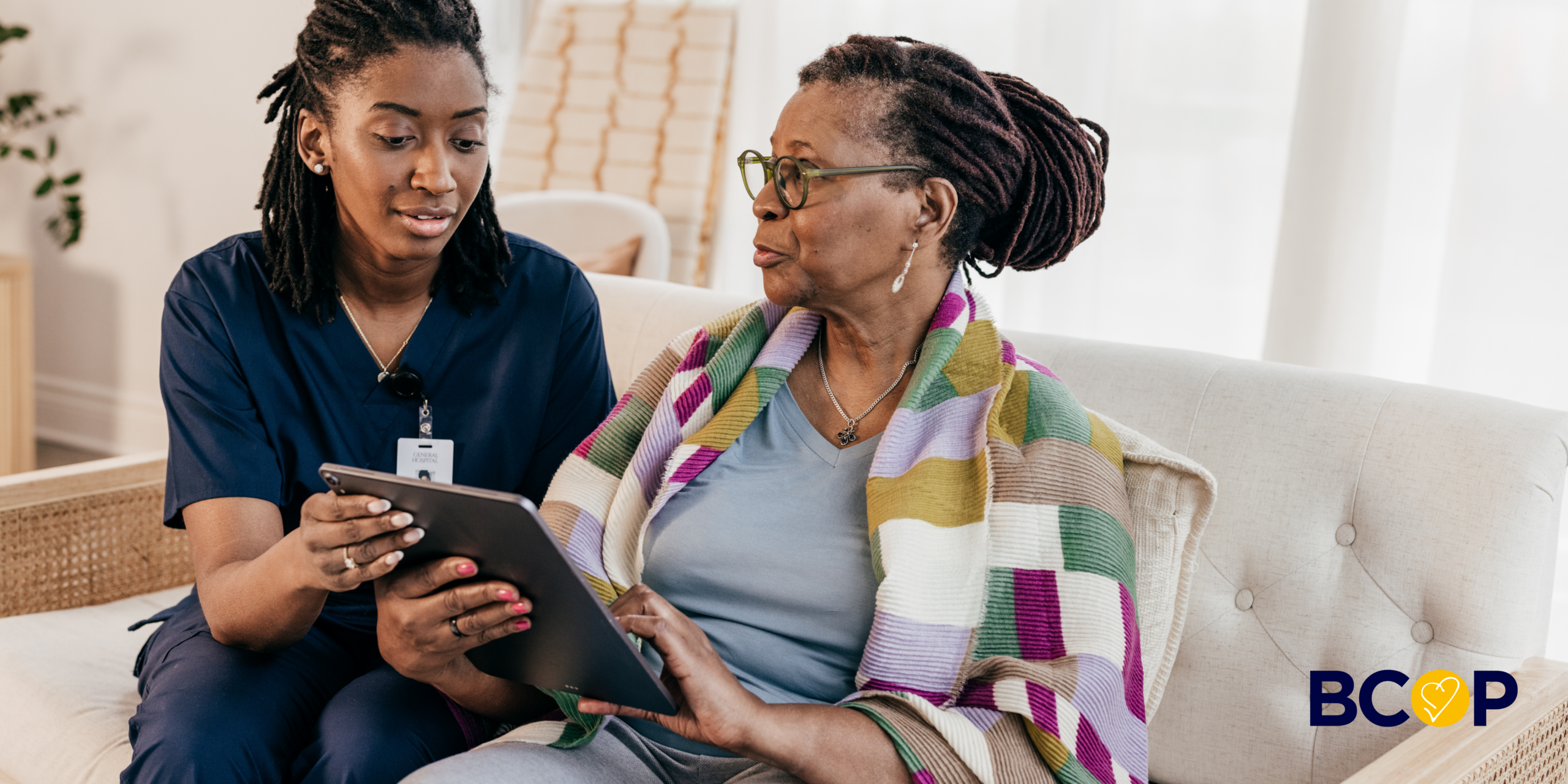 Image of a health & social care worker and an older woman looking at a tablet together