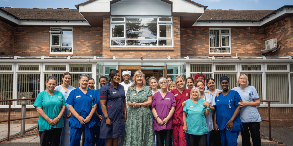 Photo of the Robert Harvey House team at the front of the nursing home with their Residential Palliative care Provider award trophy